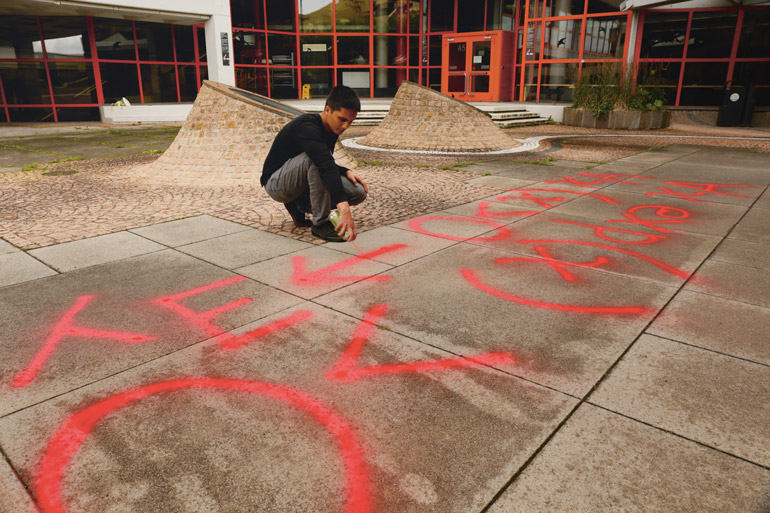 Lothar Sebastian Krapp sprüht mit Kreidespray eine symbolische Formel auf den Innenhof der Uni Konstanz